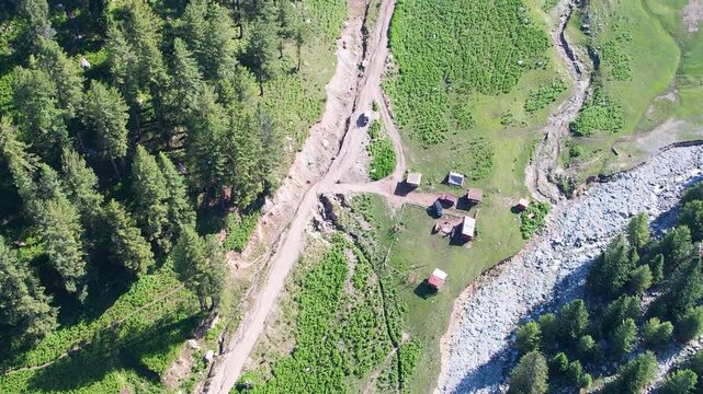 Aerial view of campsites beside a mountain stream in the highland forest of Dir District, Pakistan