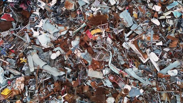 A horizontal drone top-down shot capturing a massive pile of industrial scrap metal, rusty iron, and materials waiting for sorting and sustainable recycling process in Preveza region, Greece.