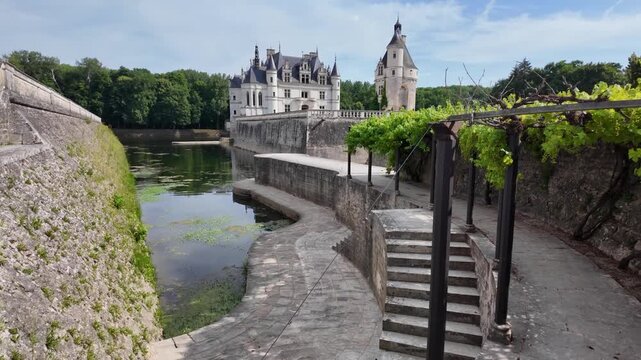 Summer view of Ch&acirc;teau de Chenonceau featuring a charming pergola covered with grapevines near the castle and overlooking the historic grounds.
