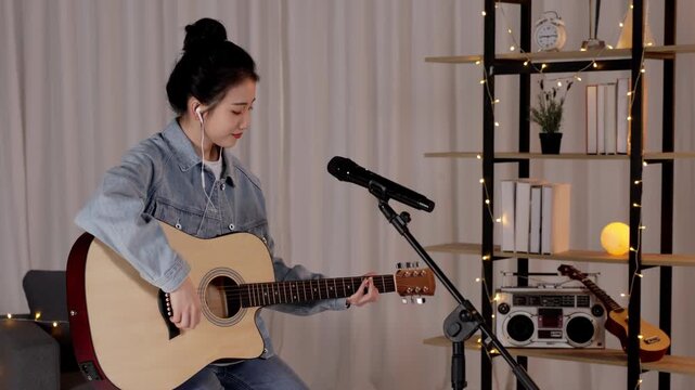 Focused artist musician practicing acoustic classical guitar, singing song with microphone in studio. Guitarist player woman string finger music fretboard play musical instrument for rock, metal track