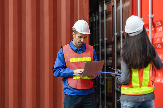 Logistics engineers using laptop to check shipping containers at cargo terminal, Professional team working with laptop and clipboard at container shipping port