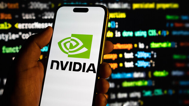 Hand holding a smartphone displaying the nvidia logo against a background of computer code