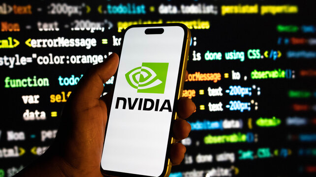 Hand holding a smartphone displaying the nvidia logo against a background of computer code