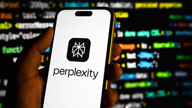 Hand holding a smartphone displaying the perplexity ai logo against a blurred background of computer code