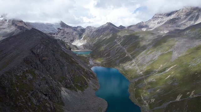 Drone view of Baimalincuo and Zhegong three lakes in Mount Kula Kangri in sunny cloudy day, well-built hiking trail circling its shore. 4k real time footage travel concept b roll shot.