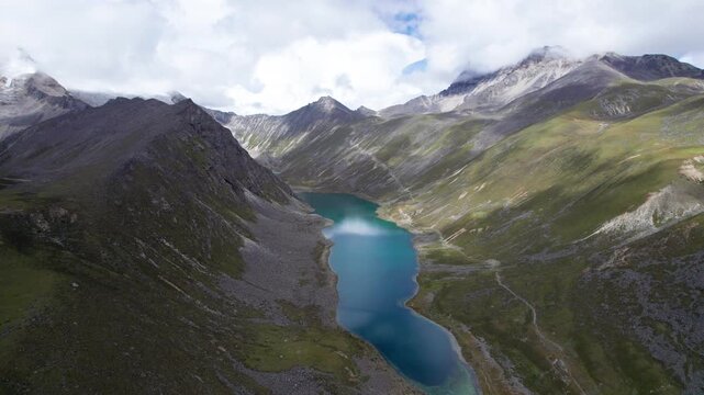 Drone view of Baimalincuo and Zhegong three lakes in Mount Kula Kangri in sunny cloudy day, well-built hiking trail circling its shore. 4k real time footage travel concept b roll shot.