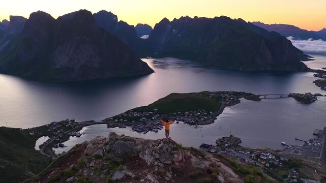 Hiker overlooking Reine village and a Norwegian fjord
