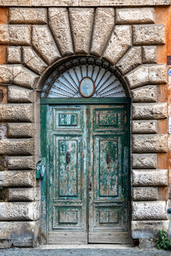 Ornate weathered green door in a stone portal, Rome, Italy