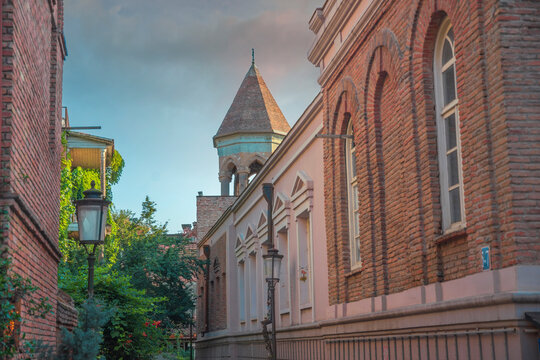 Old Tbilisi narrow street with brick building and church tower with copy space