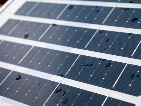 Closeup solar panel surface with water rain droplets showing photovoltaic cell grid pattern renewable clean energy technology