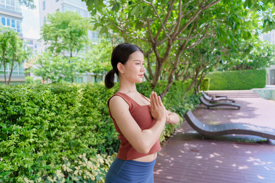 Asian Gen Z woman practicing standing yoga pose in urban park promoting wellness mindfulness and healthy lifestyle