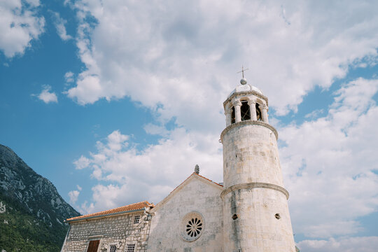 Historic seaside chapel with limestone tower. Ancient coastal church with bell tower and mountain scenery