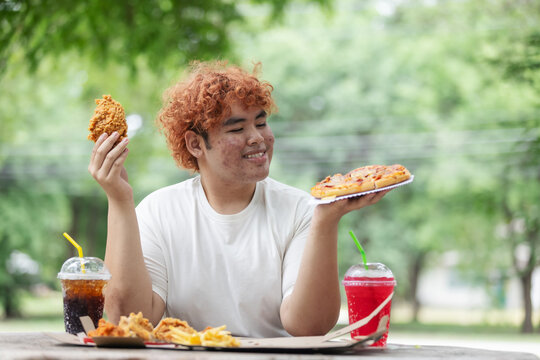 Happy Gen Z Teen Choosing Between Fried Chicken and Pizza &ndash; Junk Food Lifestyle and Fast Food Craving Outdoors