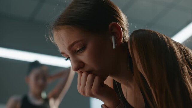 Distressed Teenager Wearing Sports Clothes, Earbud, Affected by Personal or Family Problems. Girl Tries Not to Cry Processing Difficult Thoughts. Vulnerability, Emotional Crises Faced by Modern Youth.