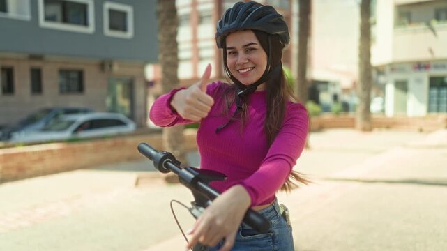 Woman on electric scooter giving thumbs up on street wearing helmet and pink sweater; optimism freedom.