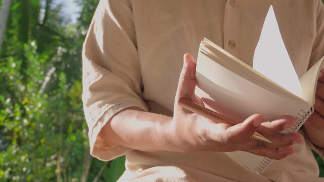 Close-up person flipping through notebook to review handwritten notes outdoors, illustrating knowledge management, information retrieval, planning, organization, productivity, and reflective thinking
