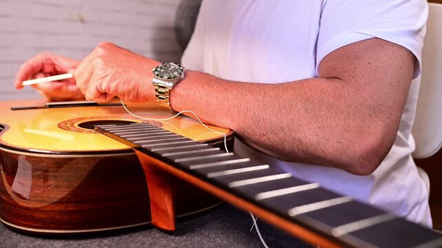 Luthier changing the nylon strings on a classical guitar