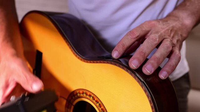 Luthier installing an equalizer preamp in a classical guitar