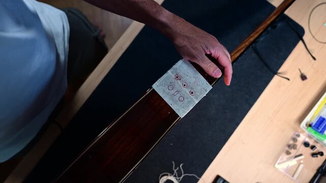 Luthier carefully drilling holes in an electric cello