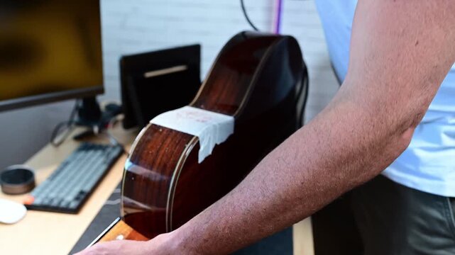 Luthier carefully drilling into an acoustic guitar for repairs