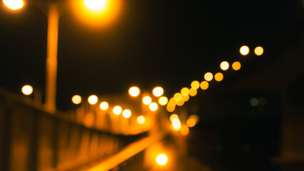 Abstract night city lights with golden bokeh and blurred street lamps along urban bridge. Moody background for transportation, travel, infrastructure, and modern city concept. Defocused streetlight. © Fahroni