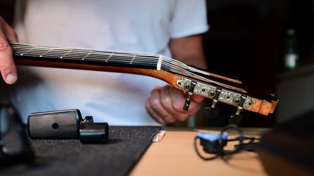Luthier carefully changing nylon strings on a classical guitar headstock