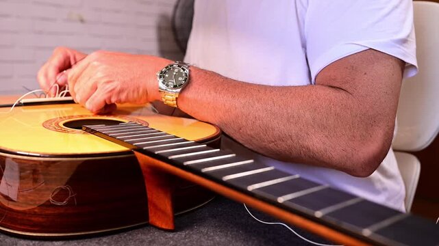 Luthier carefully restringing a classical acoustic guitar