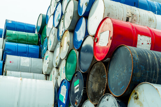 Old chemical barrels with flammable liquid warning label . Steel oil tank. Toxic waste in metal tank. Hazardous chemical barrel. Hazard waste storage in factory. Chemical barrels stack. Oil brent.