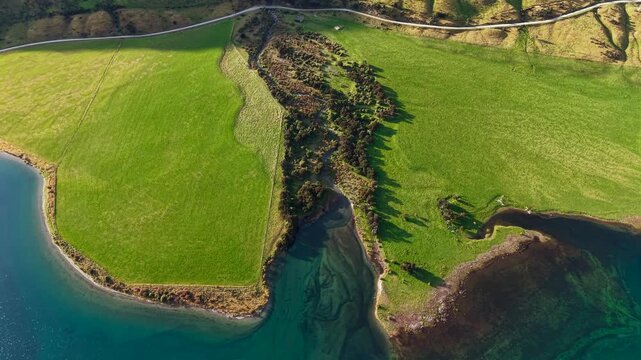 Aerial drone video of a green cove at Lake Hawea near Wanaka, New Zealand, surrounded by mountains, lake water, and dramatic South Island scenery.