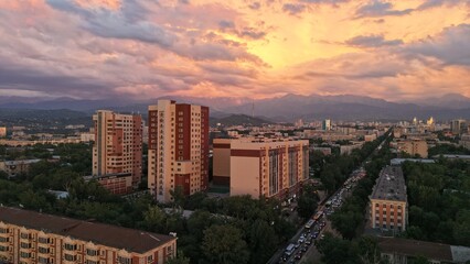 Fototapeta premium Aerial view of urban skyline at sunset with mountains in background