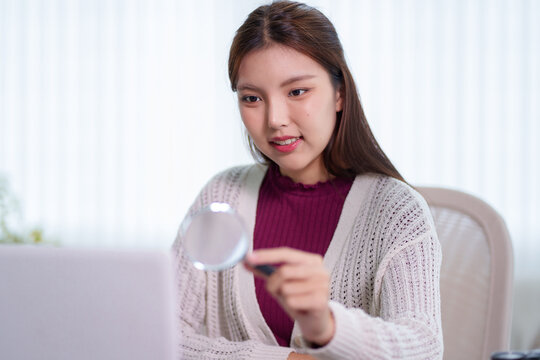 Young Asian student holding credit card while using laptop for online learning payment in home study space
