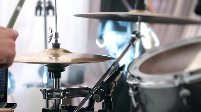 Close-up of a drummer playing a drum kit during a live music performance. Professional drum set with cymbals and microphone capturing energetic rhythm in a concert setting.