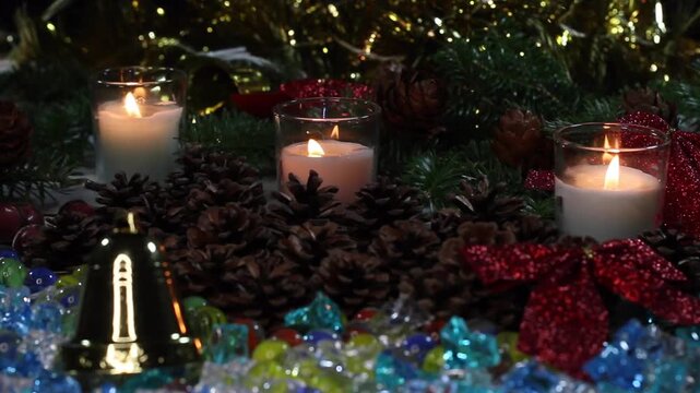 ゴールドのベルと色鮮やかな装飾に囲まれた3本のクリスマスキャンドル