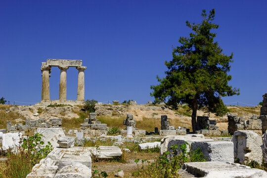 Ancient ruins of the Temple of Apollo in Corinth, Greece, under a clear blue sky.