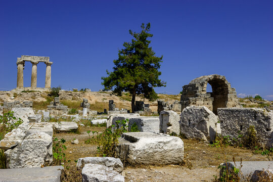 Ancient ruins of the Temple of Apollo in Corinth, Greece, under a clear blue sky.