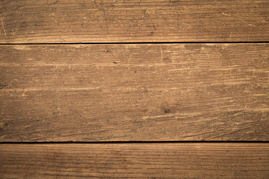 Rustic scratched weathered wooden planks texture background with horizontal grain lines, warm brown and golden-tan color palette, vignette border.