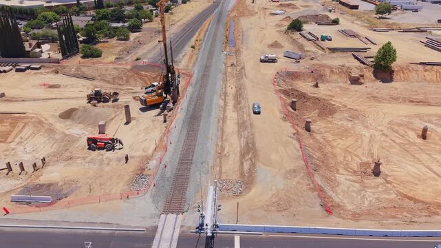 Panning Aerial Drone Shot Left to Right Over California High Speed Rail Construction With Railroad Crossing Tractor Moving Dirt Worker and Traffic