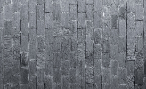 Stone cladding texture background. Gray stone wall. Stone brick for home exterior decor. Dark background for death, sad, and grief concept. Material for house wall decoration. Rough surface stone.