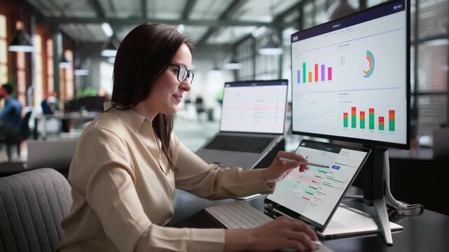 Young Woman Using Laptop And Tablet Tracking OKR Goals At Work