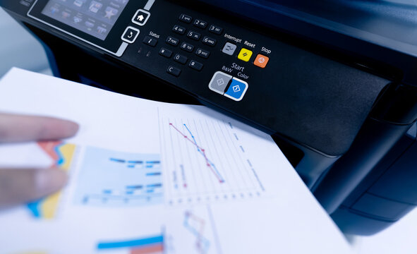 Office worker print paper on multifunction laser printer. Copy, print, scan, and fax machine in office. Modern print technology.  Photocopy machine. Document and paper work. Scanner. Secretary work.