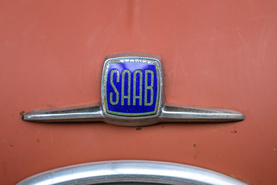 Gothenburg, Sweden - May 30 2026: Vintage SAAB emblem on weathered salmon colored classic car hood.