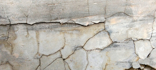 Fototapeta premium A detailed macro photo of the surface of a severely damaged gray concrete wall.