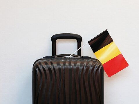 Close-up of a suitcase with a small Belgian flag, isolated against a white background. Travel, holiday, and Belgium concept.