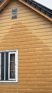 Rain blows against the artificial wood house walls. Water damage, damp walls, mold prevention concept.