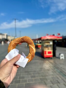 A man holding a traditional Turkish bagel - Simit