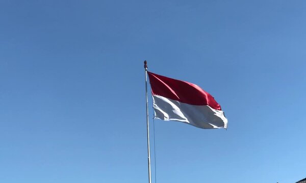 The waving national flag of Indonesia under clear blue sky