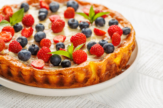 Homemade berry tart topped with fresh raspberries and blueberries