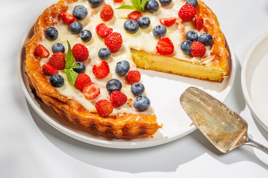 Whole berry tart with missing slice on white background