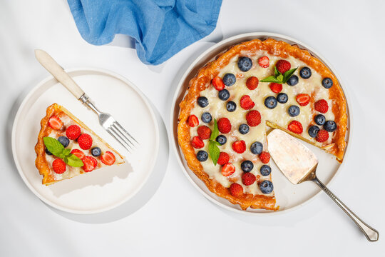 Slice of berry tart served on plate beside whole pie