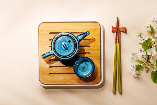 Blue teapot with blossom branch on wooden tray